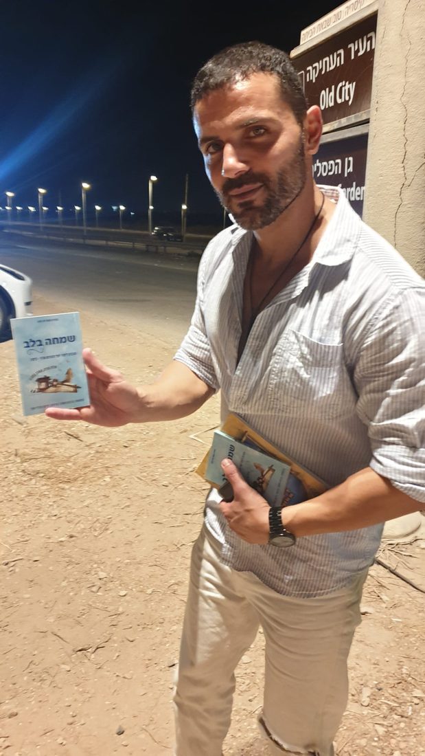 השחקן ישראל אטיאס עם חוברת שמחה בלב