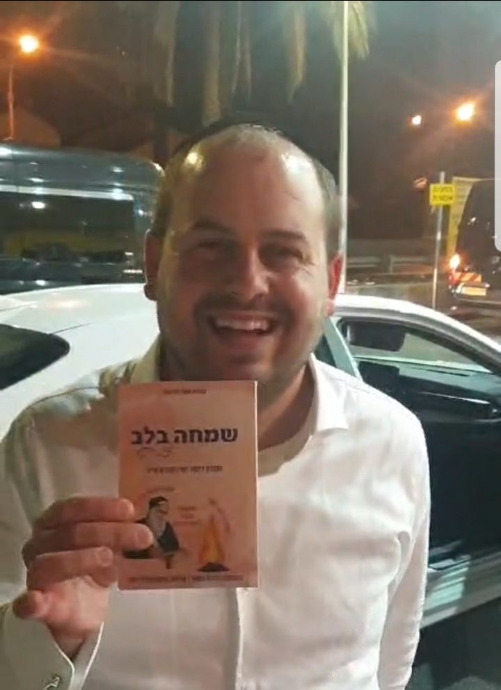 איש החסד שי גארוכר עם חוברת שמחה בלב